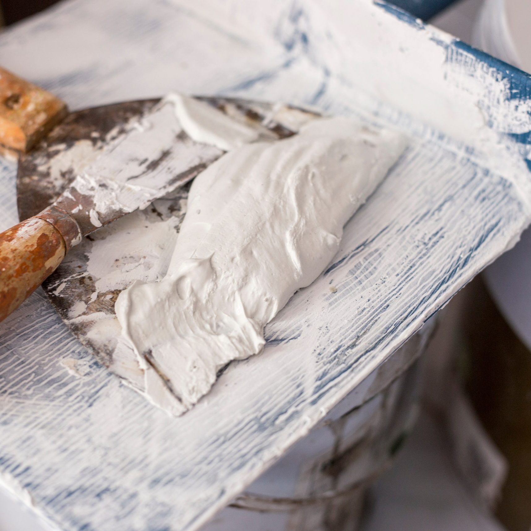 trowel and plastic plate with white plaster cement on white background in renovate building concept